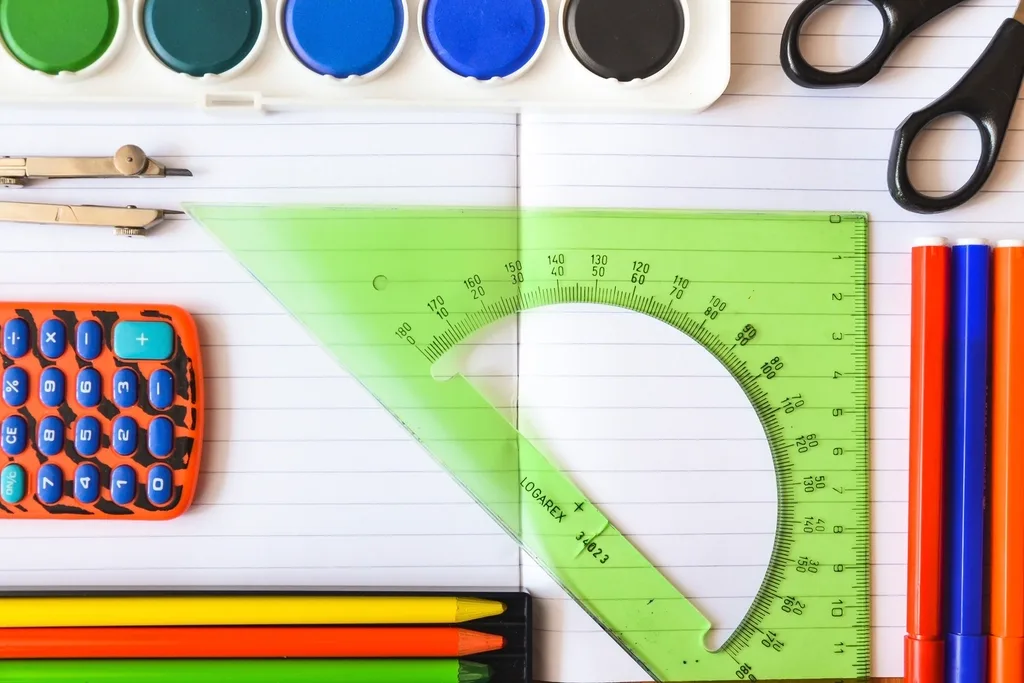 Flat-lay of school stationery: rulers, protractor, calculator, markers and paints